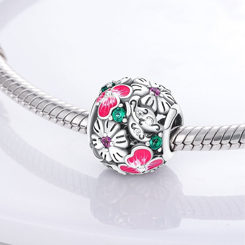 Charm redondo fabricado en plata de ley con forma de bola y flores de colores. 